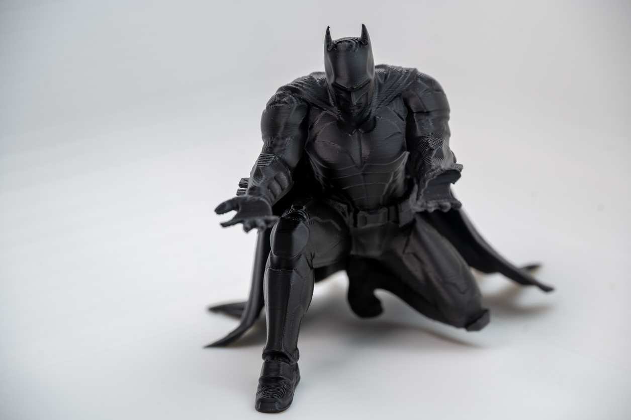 Bat inspired pen holder kneeling caped figure holding a pencil