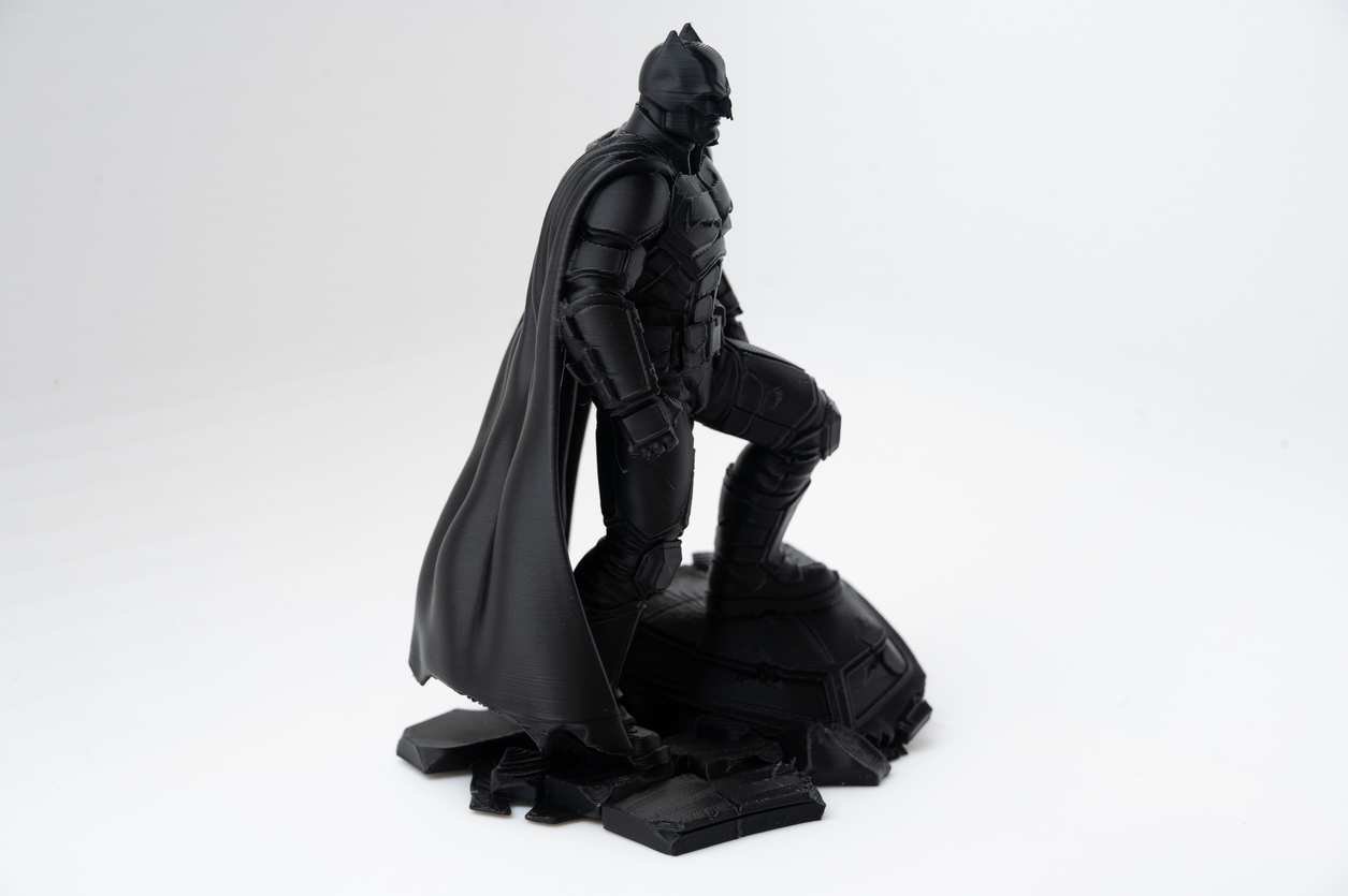 Side view of 3D printed superhero diorama with flowing cape and rooftop base