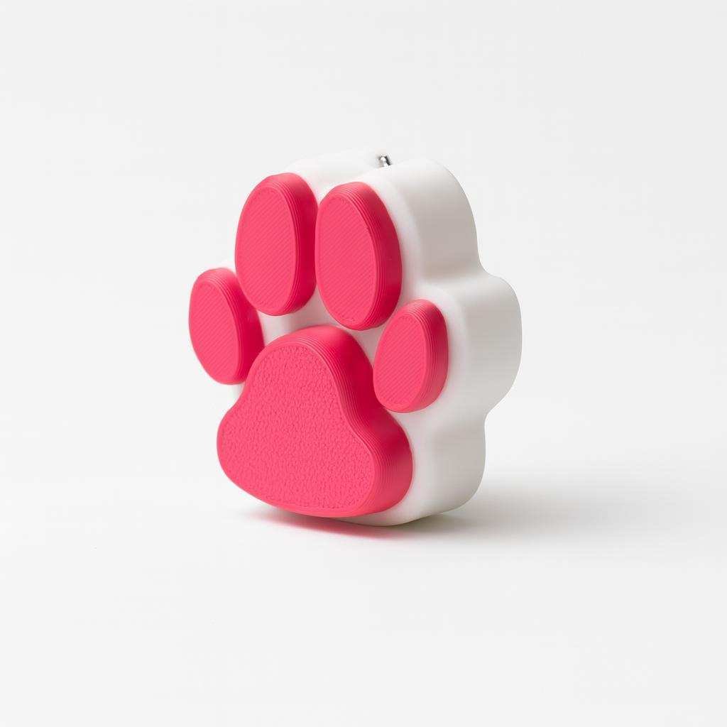 Angled view of paw print clicker keychain showing thickness and paw pads