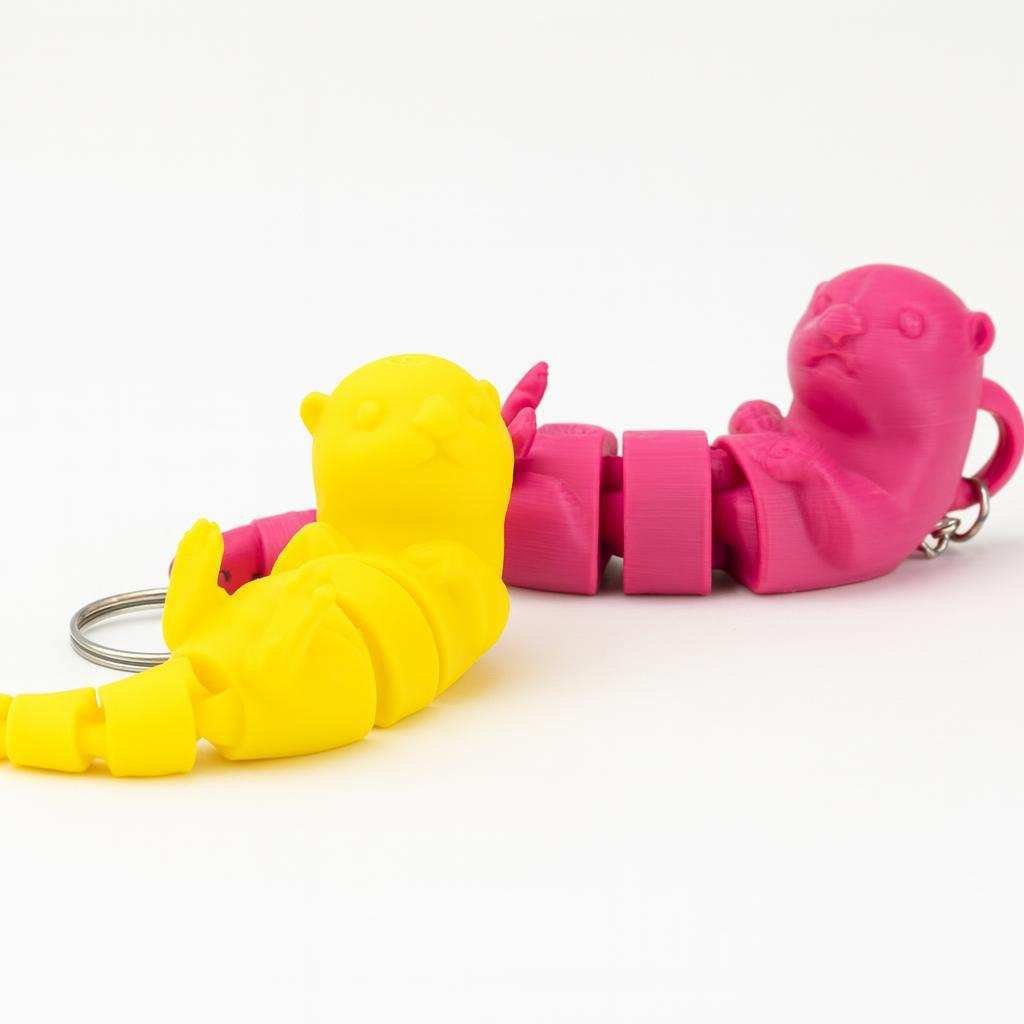 Articulated otter keychain shown in yellow and pink PLA colors
