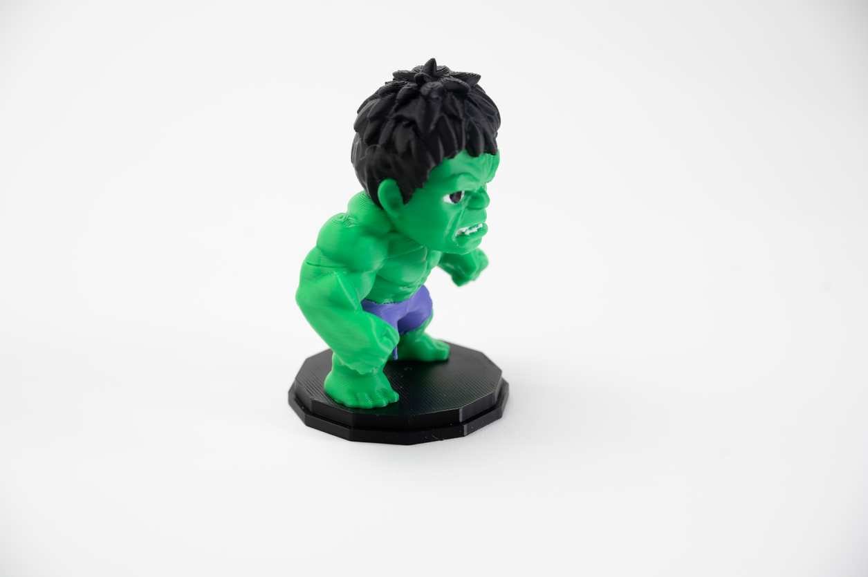 Front view of green character desk figure with purple shorts