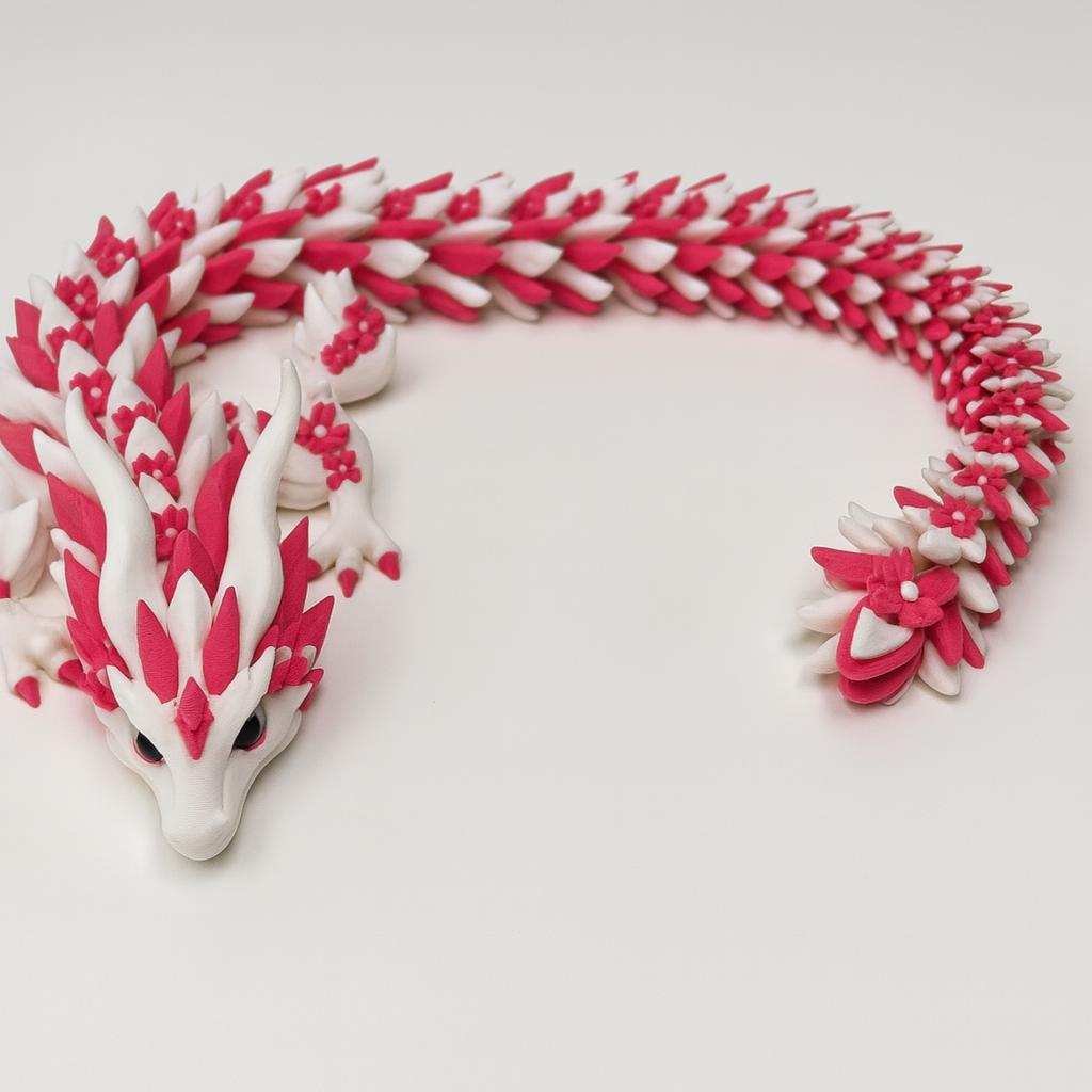 articulated 3D printed dragon in white and red PLA coiled on a tabletop